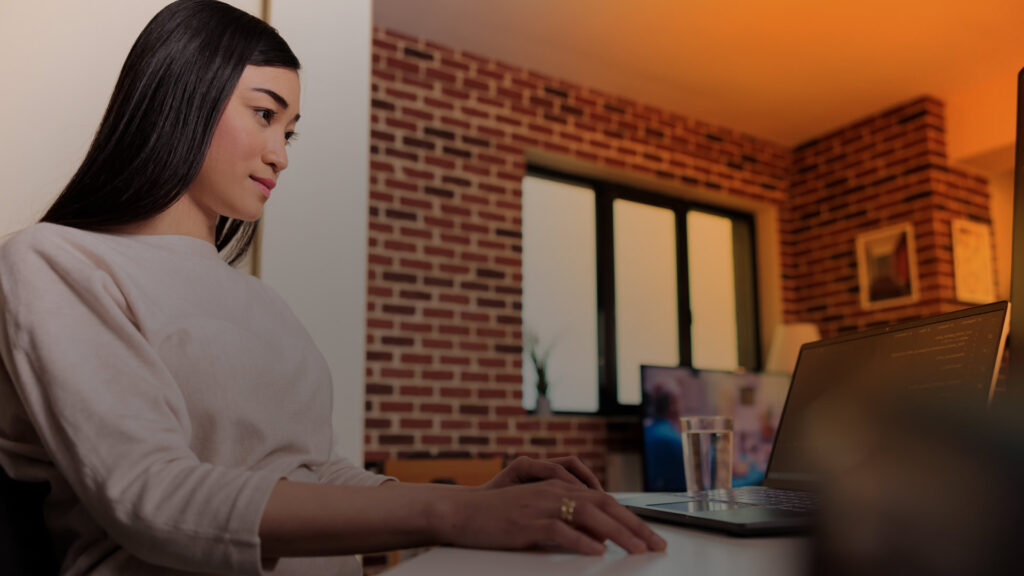 Woman reviewing information on a laptop while researching an AI-generated market answer.