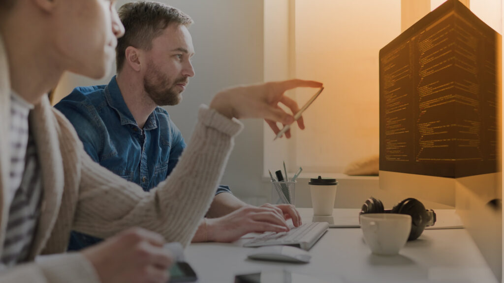 Two professionals reviewing market data and research together at a computer.